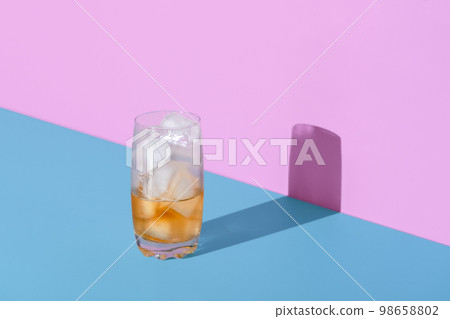 Ice tea glass, half empty, minimalist on a vibrant colored background 98658802