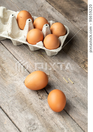 Fresh organic chicken eggs in carton or egg container on wood background. Fresh organic chicken eggs in carton or egg container on wood background. 98659220