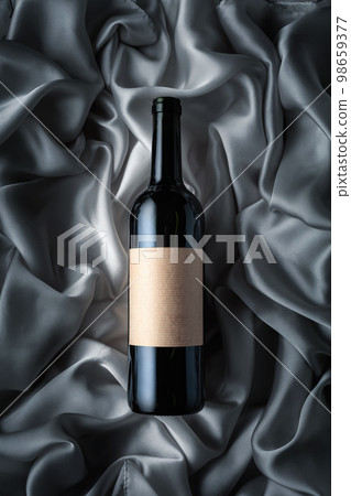 Bottle of red wine with an empty label on a satin background. Bottle of red wine with an empty label on a satin background. 98659377