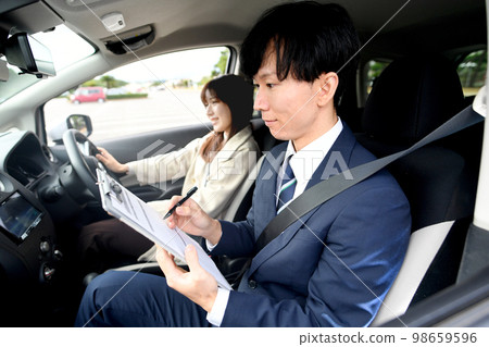 Male instructor and female student giving driving lessons Male instructor and female student giving driving lessons 98659596
