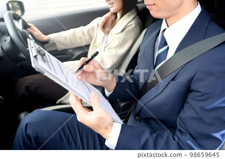 Male instructor and female student giving driving lessons Male instructor and female student giving driving lessons 98659645