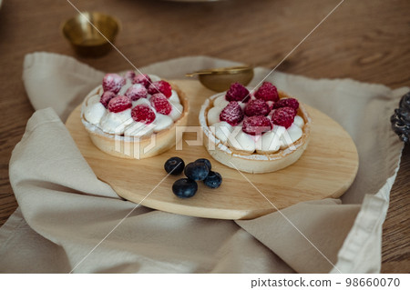 airy cakes with raspberries on a wooden tray on the table. 98660070