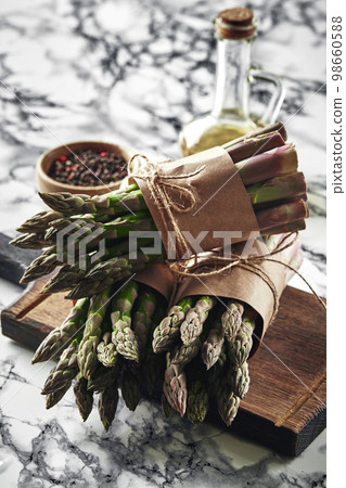 An edible, raw stems of asparagus on a marble background. An edible, raw stems of asparagus on a marble background. 98660588