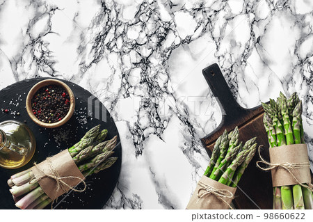 An edible, raw stems of asparagus on a marble background. 98660622