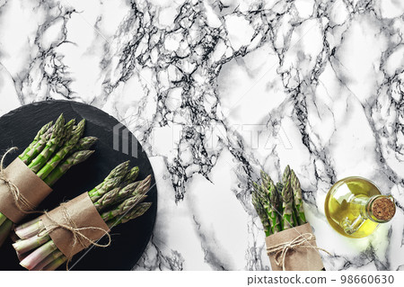 An edible, raw stems of asparagus on a marble background. An edible, raw stems of asparagus on a marble background. 98660630
