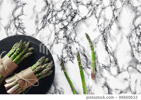 An edible, raw stems of asparagus on a marble background. An edible, raw stems of asparagus on a marble background. 98660632
