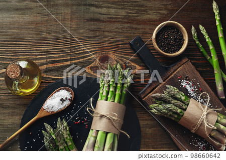 An edible, raw stems of asparagus on a wooden background. 98660642
