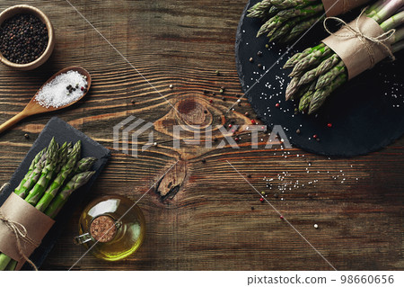 An edible, raw stems of asparagus on a wooden background. 98660656