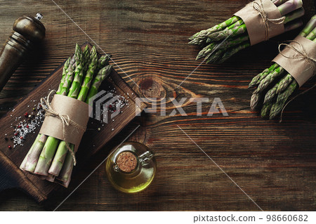 An edible, raw stems of asparagus on a wooden background. An edible, raw stems of asparagus on a wooden background. 98660682