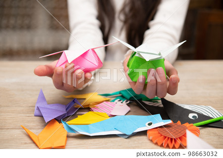 Child's hand playing with origami 98663032