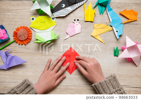 Child's hand playing with origami 98663033