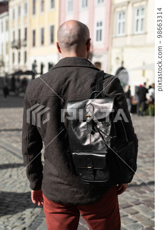 Part photo of a man with a black leather backpack with antique and retro look. Outdoors photo 98663314