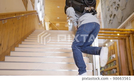 Male elementary school student climbing the stairs of the school building Male elementary school student climbing the stairs of the school building 98663561