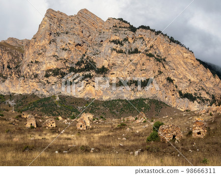 A grave stone city under a big rock. Old Ossetian family crypts in the misty mountains. Digoria region. A grave stone city under a big rock. Old Ossetian family crypts in the misty mountains. Digoria region. 98666311