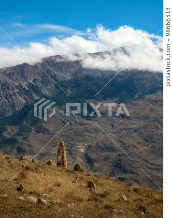 Old stone tomb, a crypt on the top of a mountain. Tombstones made of stone. Ossetia region. Vertical view. Old stone tomb, a crypt on the top of a mountain. Tombstones made of stone. Ossetia region. Vertical view. 98666313