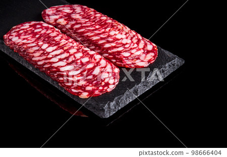 Sliced salami on a slate serving Board. Black isolated background 98666404