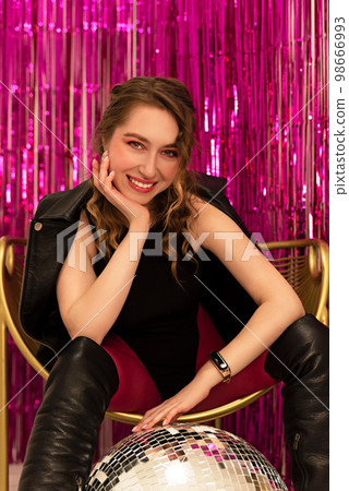 young cute girl posing on a pink background with a disco ball. 98666993