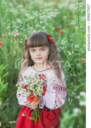 Adorable child in Ukrainian folk clothes in a field with flowers 98667007