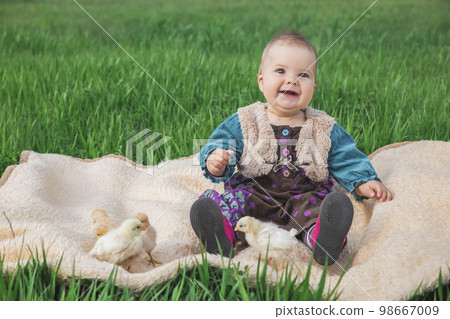 baby in a colorful dress on the lawn with chickens  98667009