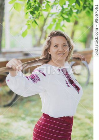 Beautiful peasant woman walks with a balance beam for buckets of water Beautiful peasant woman walks with a balance beam for buckets of water 98667061