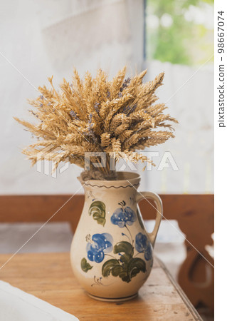 Ceramic jug with a bouquet of wheat in an old hut Ceramic jug with a bouquet of wheat in an old hut 98667074