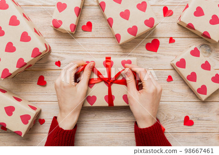 Women hands pack gifts and make decorations for the holiday, top view. Birthday and valentine present Women hands pack gifts and make decorations for the holiday, top view. Birthday and valentine present 98667461