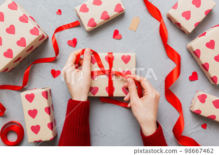 Women hands pack gifts and make decorations for the holiday, top view. Birthday and valentine present Women hands pack gifts and make decorations for the holiday, top view. Birthday and valentine present 98667462