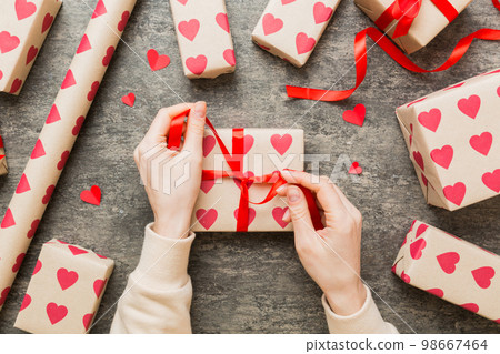 Women hands pack gifts and make decorations for the holiday, top view. Birthday and valentine present Women hands pack gifts and make decorations for the holiday, top view. Birthday and valentine present 98667464
