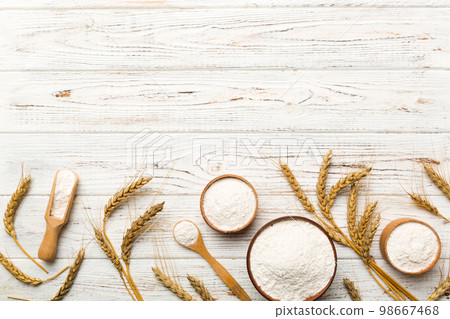 Flat lay of Wheat flour in wooden bowl with wheat spikelets on colored background. world wheat crisis 98667468
