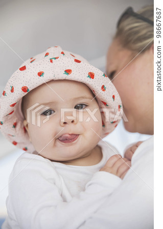 mom holds cute baby and the child shows the tongue 98667687