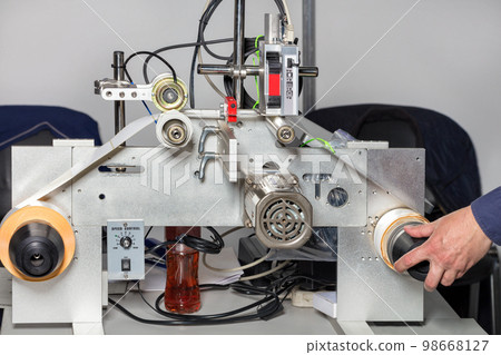 A fitter's hand adjusts a laser print line on self-adhesive drum-wound labels. A fitter's hand adjusts a laser print line on self-adhesive drum-wound labels. 98668127