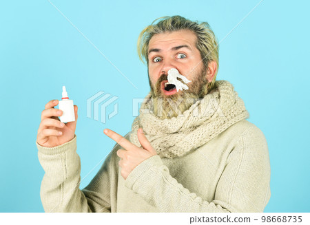 Cold flu remedies. Runny nose recovery. Health care concept. Runny nose and symptoms of cold. Fast recovery. Man scarf hold nasal spray. Medicines effective recovery. Allergy medical treatment 98668735