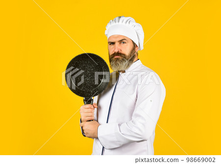 Nonstick cookware. Frying without oil. Professional kitchenware. Bearded chef preparing breakfast. Nonstick pan for frying. Enameled cooking vessels. Man hold pan. Frying meal. Healthy food Nonstick cookware. Frying without oil. Professional kitchenware. Bearded chef preparing breakfast. Nonstick pan for frying. Enameled cooking vessels. Man hold pan. Frying meal. Healthy food 98669002
