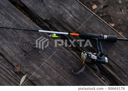 Spinning reel and bait for predatory fish. Fishing tackle on a wooden background. 98669176