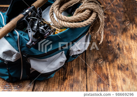 Fishing bag with items for fishing. A fishing rod with a reel and a tackle bag. Fishing composition. 98669296