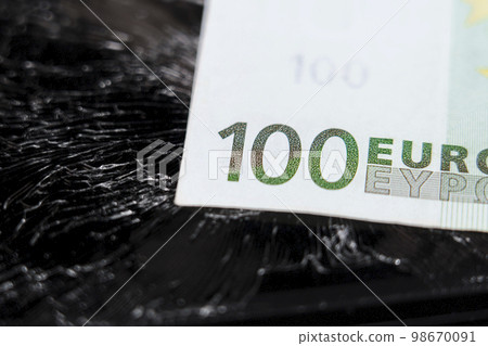 One hundred euro banknote on a cracked crushed broken black surface. Concept of inflation with devaluation and economic crisis idea One hundred euro banknote on a cracked crushed broken black surface. Concept of inflation with devaluation and economic crisis idea 98670091