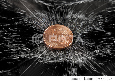 One cent European coin on a black crushed cracked surface. Concept of economic crisis One cent European coin on a black crushed cracked surface. Concept of economic crisis 98670092