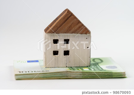 Cracked wooden house model on stack of euro banknotes close-up on a white background. The concept of financial costs for house renovations and insurance Cracked wooden house model on stack of euro banknotes close-up on a white background. The concept of financial costs for house renovations and insurance 98670093
