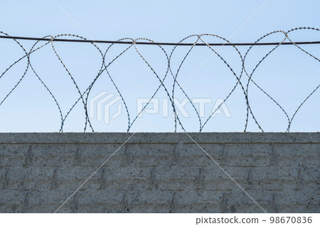 fence with barbed wire on a blue sky background 98670836