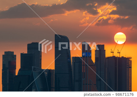 The setting sun over the skyscrapers of the Moscow City office center on a summer evening. Sunset. 98671176