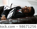 Young mixed-race business man is holding he bag while sleeping on the couch. Exhausted, Illness, tired, stressed from overworked concepts 98671256