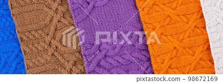 Knitted blue, lilac, brown, orange and beige background. Large knitted fabric with a pattern. Close-up of a knitted blanket. Banner 98672169