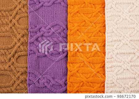 Knitted beige, lilac, brown and orange background. Large knitted fabric with a pattern. Close-up of a knitted blanket. Knitted beige, lilac, brown and orange background. Large knitted fabric with a pattern. Close-up of a knitted blanket. 98672170