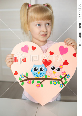 A blogger girl makes a felt craft for Valentine's Day in the shape of a heart. The concept of children's creativity and handmade. 98672190