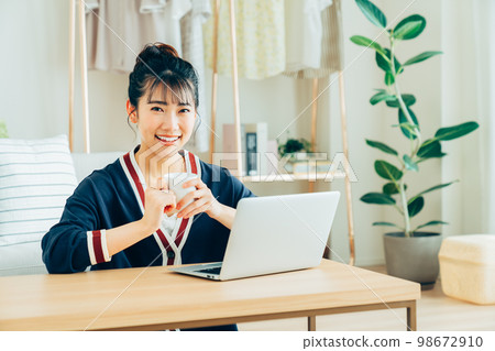A young lady who plays a personal computer in the living room 98672910