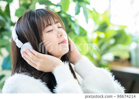 A young woman listening to music with headphones 98674214