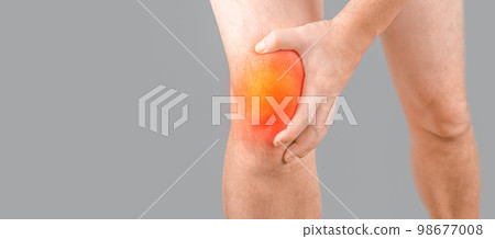 Man with knee pain on gray background. Man leg knee with red dot. Knee injury, sprain, arthritis or meniscus. Man having problems in knee joint. Closeup view. copy space 98677008