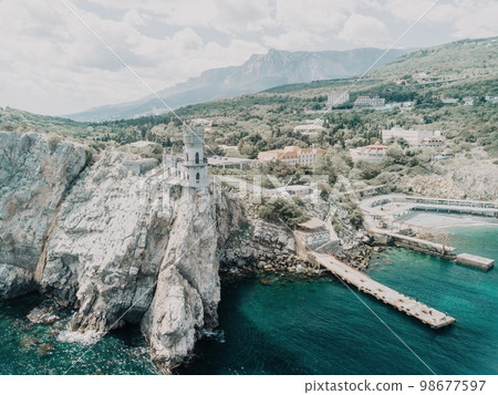 Crimea Swallow's Nest Castle on the rock over the Black Sea. It is a tourist attraction of Crimea. Amazing aerial view of the Crimea coast with the castle above abyss on sunny day. 98677597