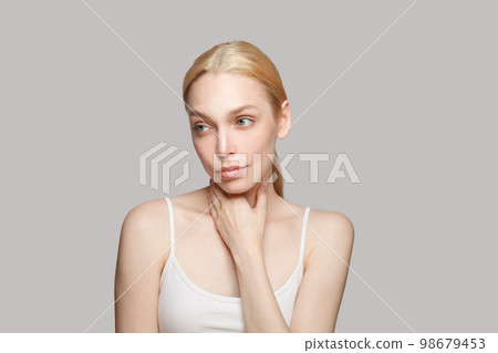 Pensive gorgeous woman touching her neck on grey background. Beauty, cosmetics, skincare, glamour Pensive gorgeous woman touching her neck on grey background. Beauty, cosmetics, skincare, glamour 98679453
