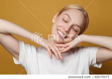 Close up portrait of perfect young woman smiling on bright yellow background 98679473